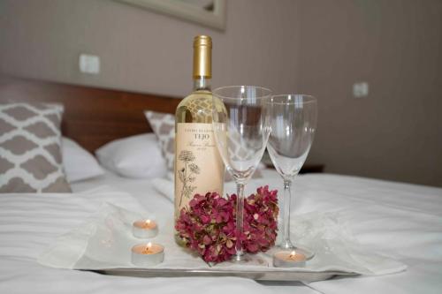 热舒夫珀洛尼亚酒店的床上有一瓶葡萄酒和两杯酒