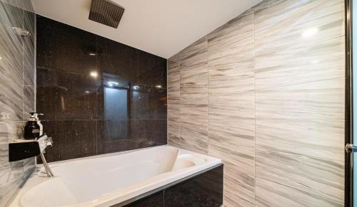 仁川市Tomoto Hotel的浴室设有白色浴缸和瓷砖墙。