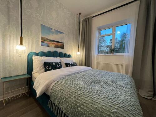 WellingCentral Welling Flat的一间卧室配有一张带蓝色床头板的床和窗户