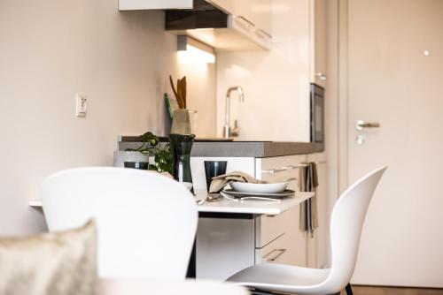 多恩比恩Smart Living Dornbirn的厨房配有桌子和两把白色椅子