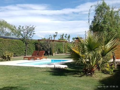 圣拉斐尔La Cabaña de Eco Verde的院子内的游泳池,旁边设有两个长椅