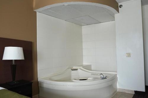 沃特福德镇American Inn & Suites的白色的客房设有一张床和浴缸。