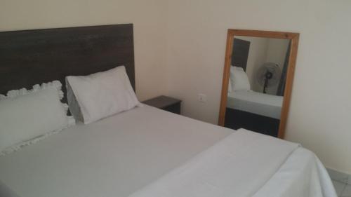 基加利PagersHome Suites - Classic Nyarutarama的卧室配有白色的床和镜子