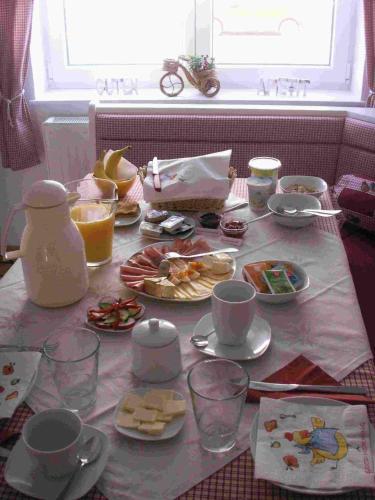MarcheggGästehaus Bett-i的餐桌,带食物,杯子和盘子