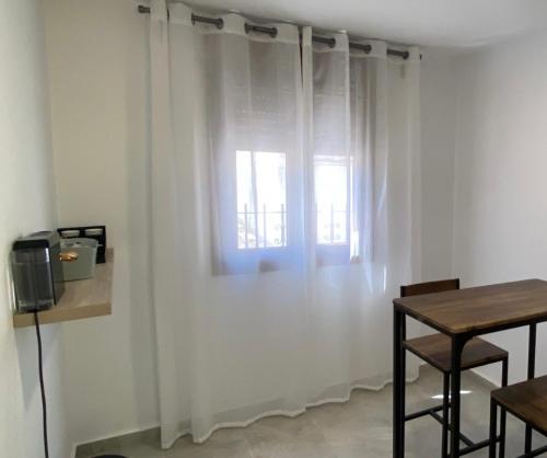 贝纳卢普-卡萨斯维耶哈斯Suites Benalup Centro的一间设有白色窗帘、桌子和窗户的客房
