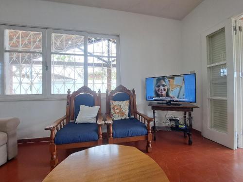 卡波布里奥3 QTS Churrasqueira Garagem perto do Forte e Ilha do Japonês的客厅配有2把椅子和平面电视