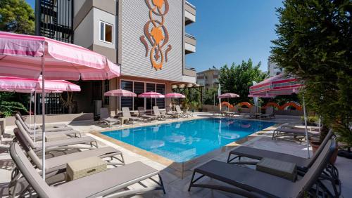 安塔利亚Lara Olympos Hotel的酒店旁的游泳池配有椅子和遮阳伞