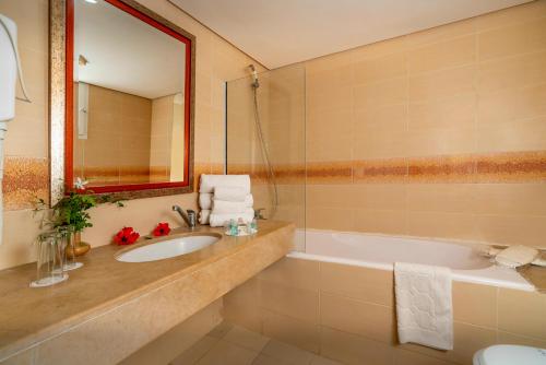 哈马马特Le Hammamet Hotel & SPA的一间带水槽、浴缸和镜子的浴室