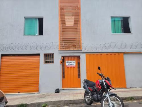 贝洛奥里藏特Kitinet Central的停在一座带橙色门的建筑前面的摩托车