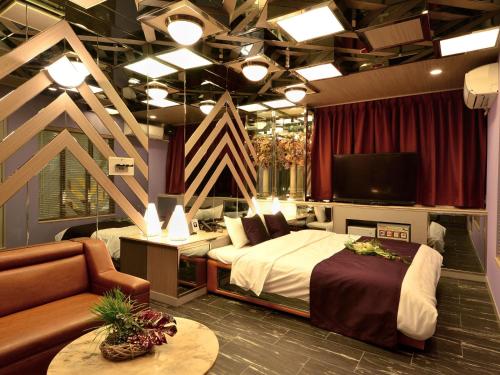 堺市HOTEL CHANT - Adult Only 大人専用的一间卧室配有一张床、一台电视和一张沙发