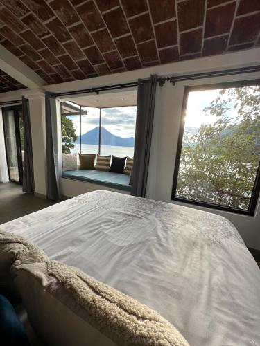圣克鲁斯拉拉古纳Atitlan Sunset Lodge的一间卧室设有一张大床和大窗户