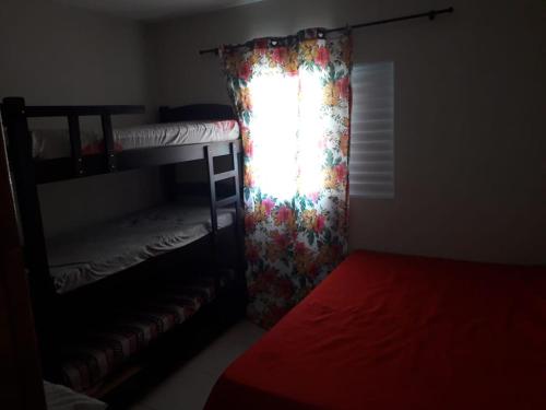 瓜鲁柳斯casa na praia Itanhaém的一间卧室配有一张双层床和一个带窗帘的窗户。