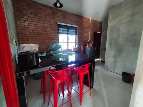 珍南海滩The RedBrick's Homestay Langkawi的黑色柜台上带红色凳子的厨房