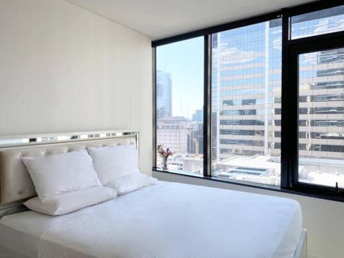 悉尼Sydney CBD Luxury Furnished Apartment & City Views的配有大窗户的客房内的白色床