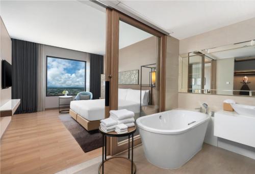 罗勇罗勇市中心假日套房酒店的带浴缸的浴室和1间带1张床的卧室
