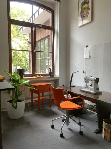 科隆Art Loft的一个带橙色椅子、书桌和显微镜的办公室