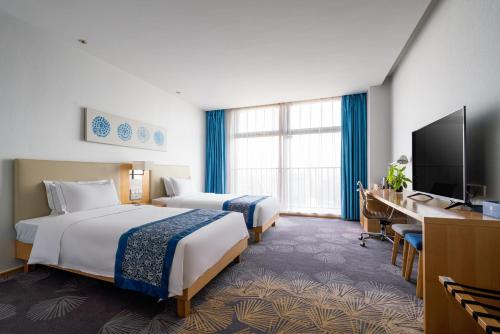 石家庄石家庄诺华廷酒店 Novlion hotel的酒店客房设有两张床和电视。