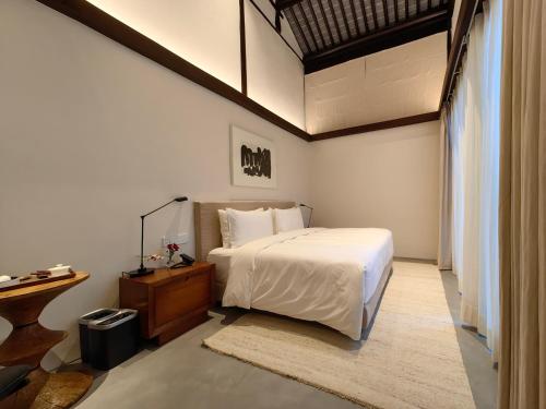 苏州苏州畅园有熊酒店的卧室配有白色的床和木桌