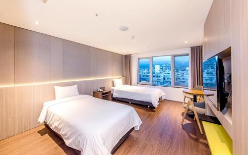 西归浦市Noblepia Hotel的酒店客房设有两张床和一台平面电视。
