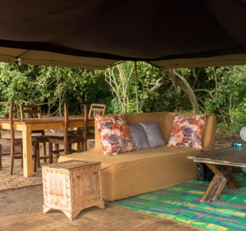 KwangwaziNje Bush Camp的一张沙发,在帐篷里,配有一张桌子