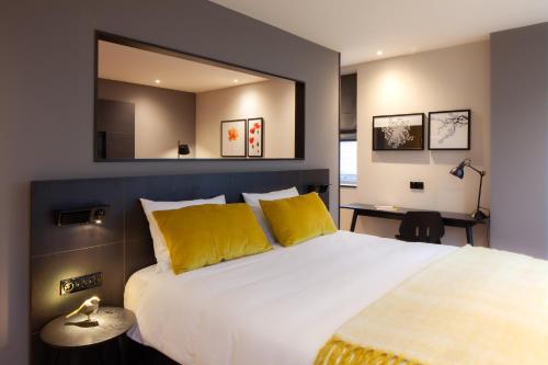莱顿莱顿金色郁金香中心酒店的一间卧室配有一张大床、黄色枕头和镜子