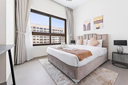 迪拜StoneTree - Spacious 2BR Apartment in Golf Views Block A的一间卧室设有一张大床和一个大窗户