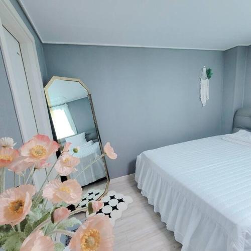 富川市Goose Stay的一间卧室配有床、镜子和鲜花