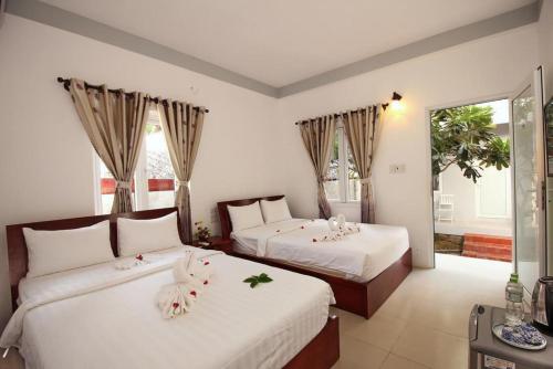 潘切Nu Cuoi Mui Ne Hotel & Restaurant的一间卧室配有两张鲜花床。
