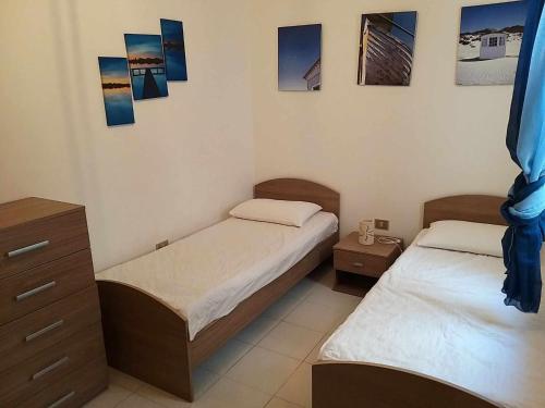 丽都玛里尼Res lido marini的卧室内的两张床,墙上挂有照片