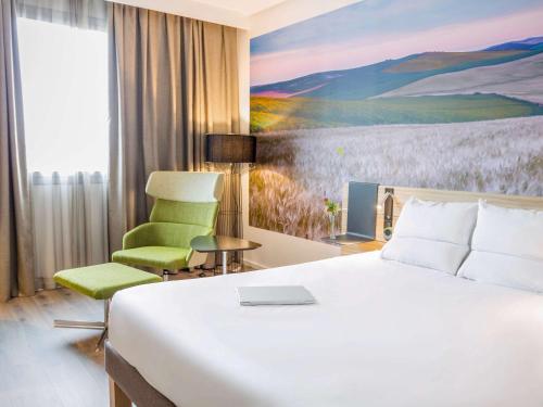 塞维利亚Novotel Sevilla的酒店客房,配有一张床和一把绿色椅子