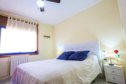 坎布里尔斯Roger ONLY FAMILIES的一间卧室配有一张带蓝色枕头的床和一扇窗户。