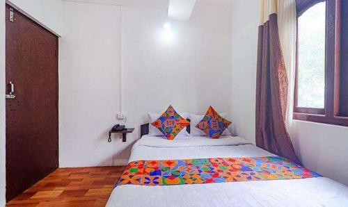 甘托克FabExpress Laxmi Niwas的一间卧室配有一张带彩色毯子的床