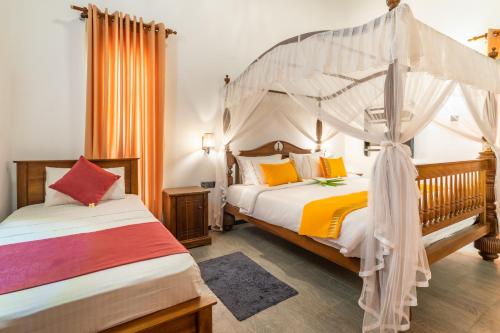MullaittivuAlai Resort的一间卧室配有两张床和一张天蓬床。