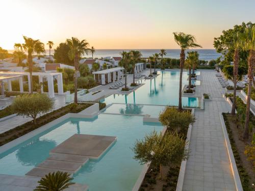 法里拉基Grecotel Lux Me Dama Dama的享有棕榈树游泳池和大海的顶部景致