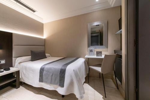 潘普洛纳Hotel Europa的酒店客房带一张床、一张书桌和一面镜子