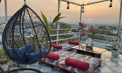 乌代浦Raahi Backpacker's Hostel的阳台配有2把秋千椅和桌子