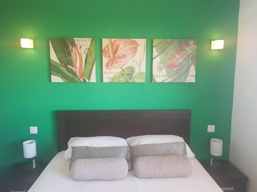 圣玛丽亚BCV - Private 1 Bedroomed Apartment Dunas Resort 3044 and 3077的一张绿色的墙,床上方有四张照片