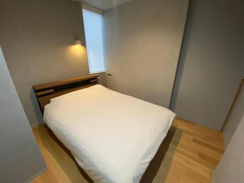 名古屋Villa Monica EAST的一间小卧室,配有一张白色的床和窗户