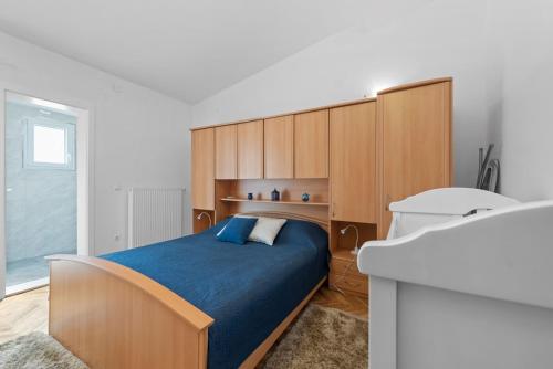 NeorićVilla Almas - Heated Pool, Sauna, Gym and Tennis Court的一间卧室配有一张蓝色的床和木制橱柜。