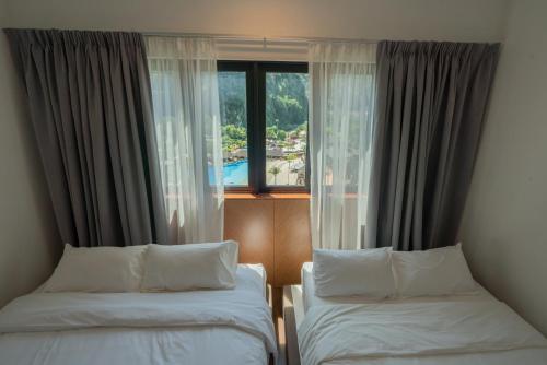 怡保Ipoh Tambun Sunway Onsen Suite 3R2B Miya的酒店客房设有两张床和窗户。