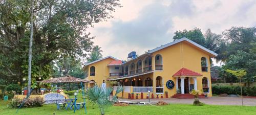 比纳里姆Carina Beach Resort - 10mins walk to Benaulim Beach的黄色的房子,带桌椅的院子