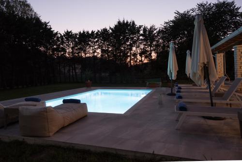 斯达林The Green House Villa (with private pool) Corfu的游泳池配有沙发、椅子和遮阳伞