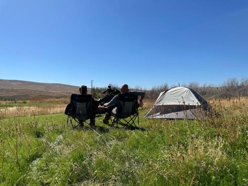 NachesInfidel Acres Motorcycle tent spaces.的一组三人坐在帐篷旁边的椅子上