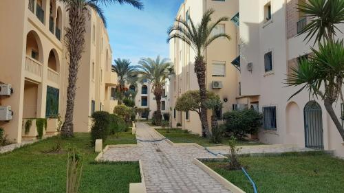 哈马马特Appartement résidence Port yasmine hammamet的两栋棕榈树建筑之间的人行道