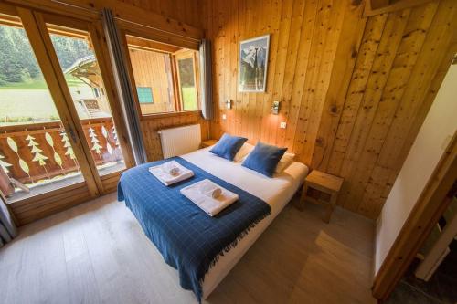 莫尔济讷Chalet Haut Fort Prodains Lift - Mountain Voyages的一间卧室配有一张带蓝色床单的床和一扇窗户。
