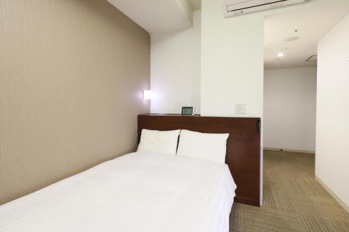 高松多美迎高松酒店的一间卧室配有一张带白色床单的大床