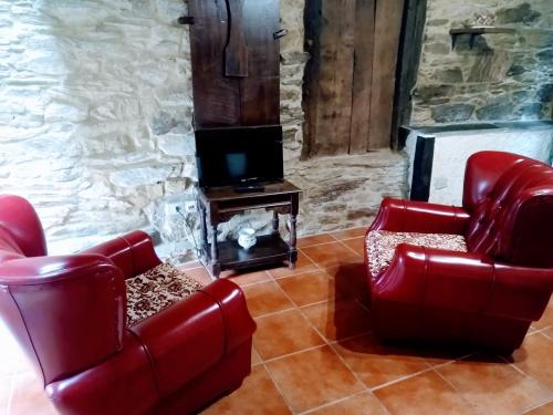 特里亚卡斯特拉Casa Pacios by M de Santiago的客厅配有2把红色椅子和电视