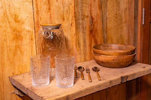 伊基托斯Aparthotel Ayahuaska for SOLO travelers的木架,带两杯玻璃和碗