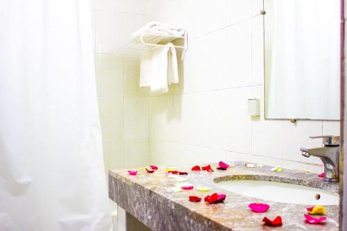 非斯Hotel Nouzha的浴室在柜台上设有带玫瑰的盥洗盆
