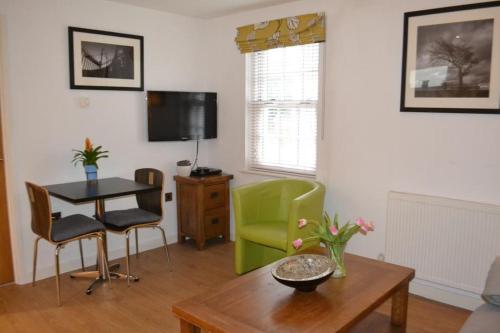 切尔滕纳姆Entire apartments in the heart of the Suffolks - GL50 Apartments的客厅配有桌子和绿色椅子